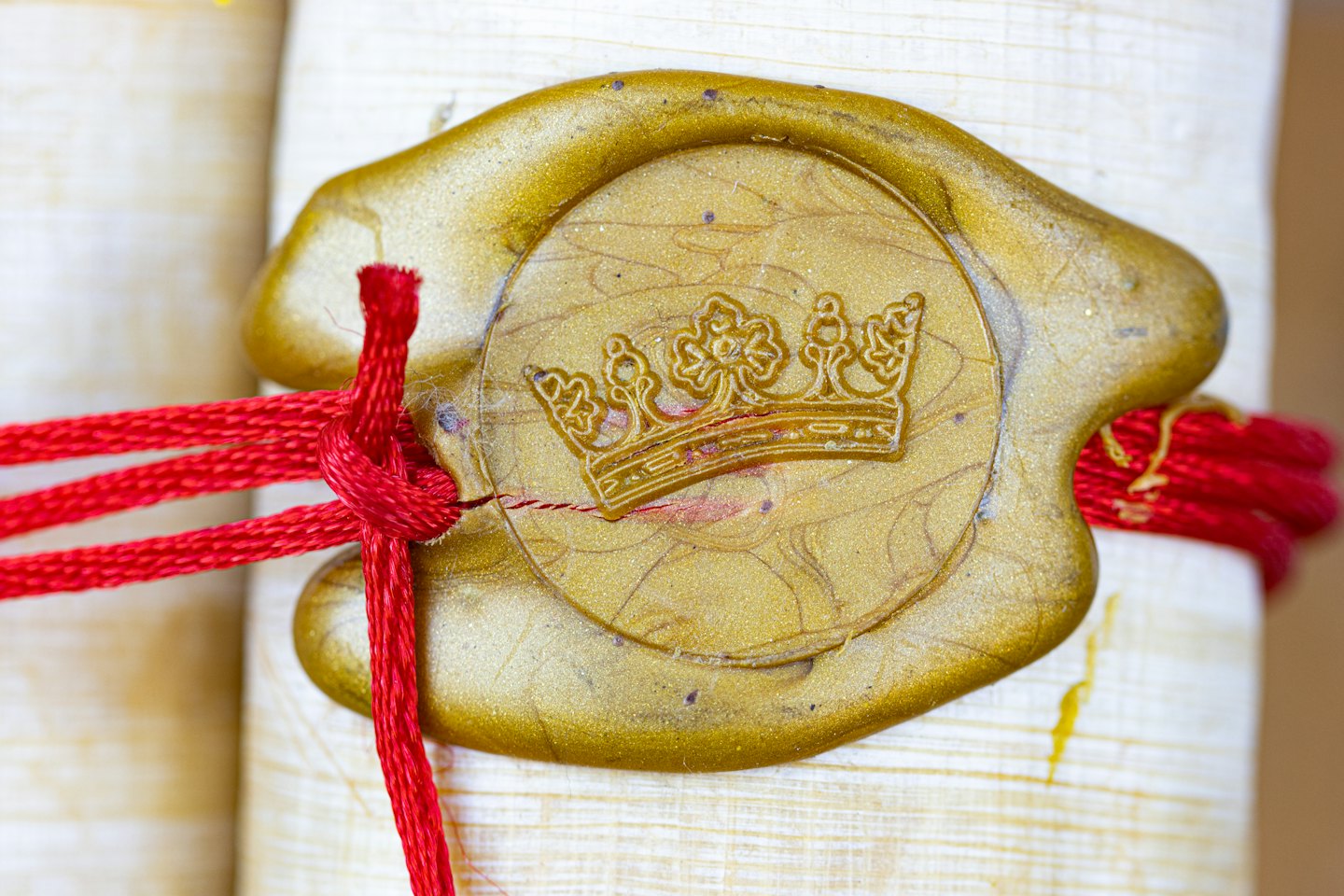 Golden wax seal with crown emblem tied with red string.
