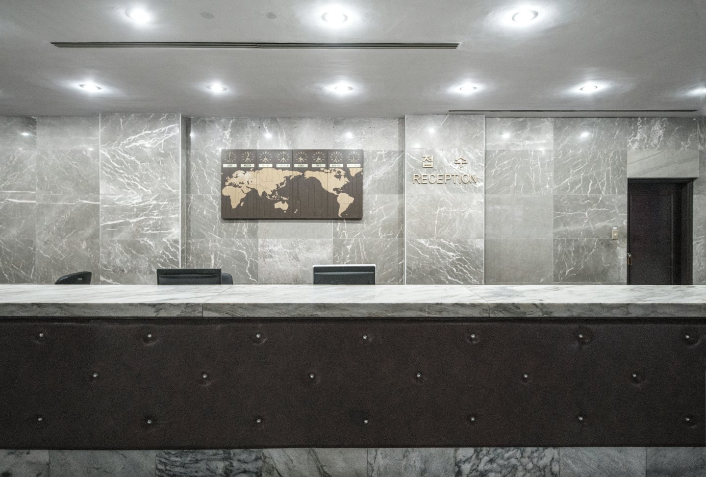Modern reception desk with world map and clocks.